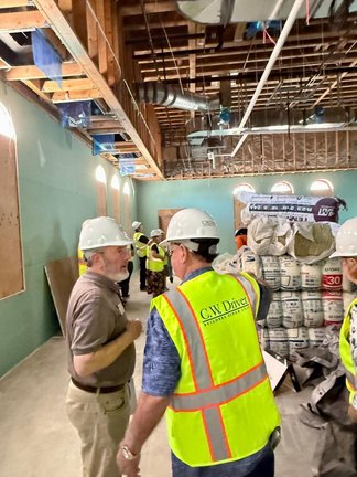 Rotarians in hard hats touring the under-construction wing of the Beaumont Library