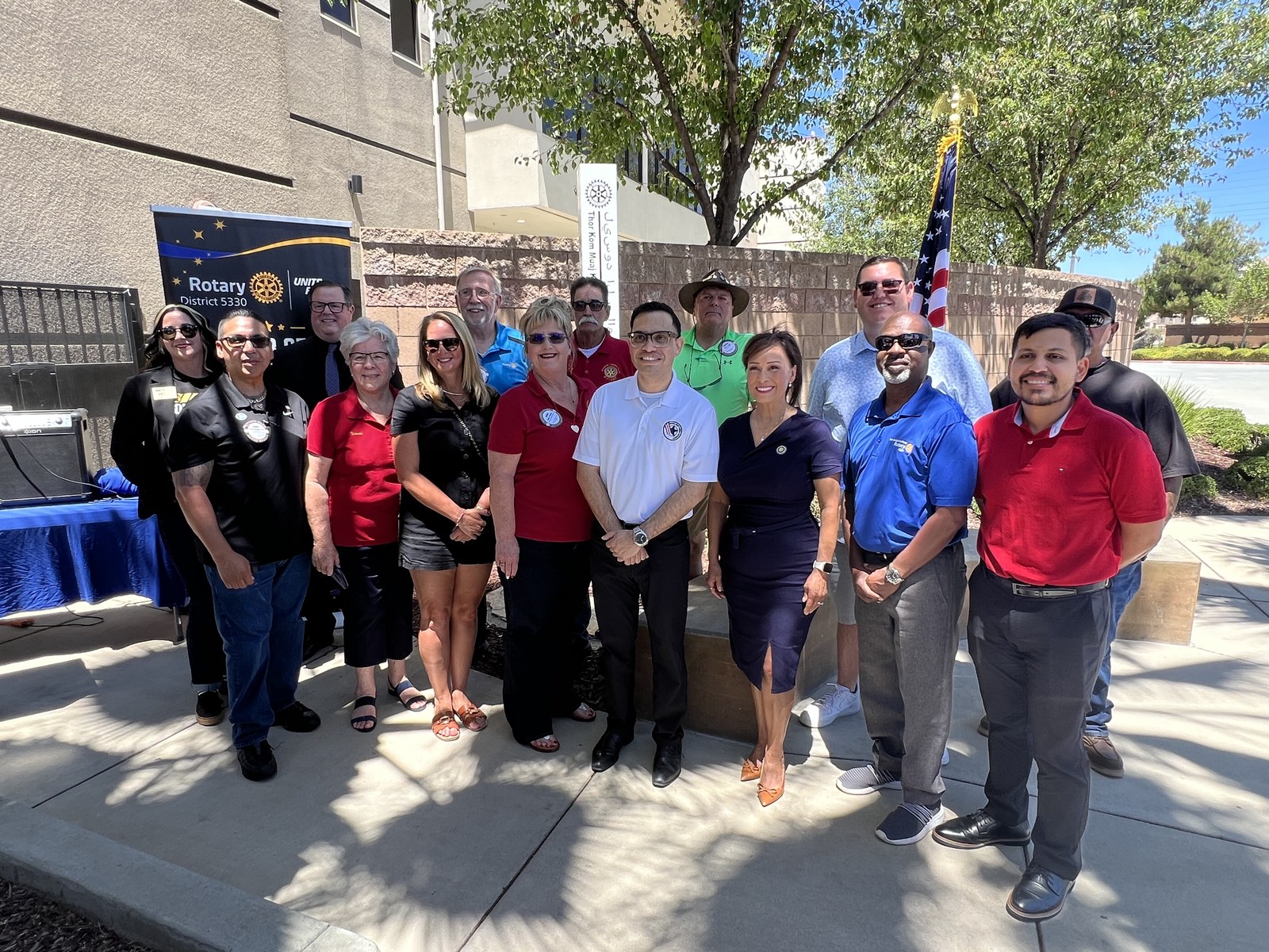 Rotarians and community leaders gather beside the newly unveiled Peace Pole at the Chatigny Center, with the Rotary District 5330 banner and a U.S. flag