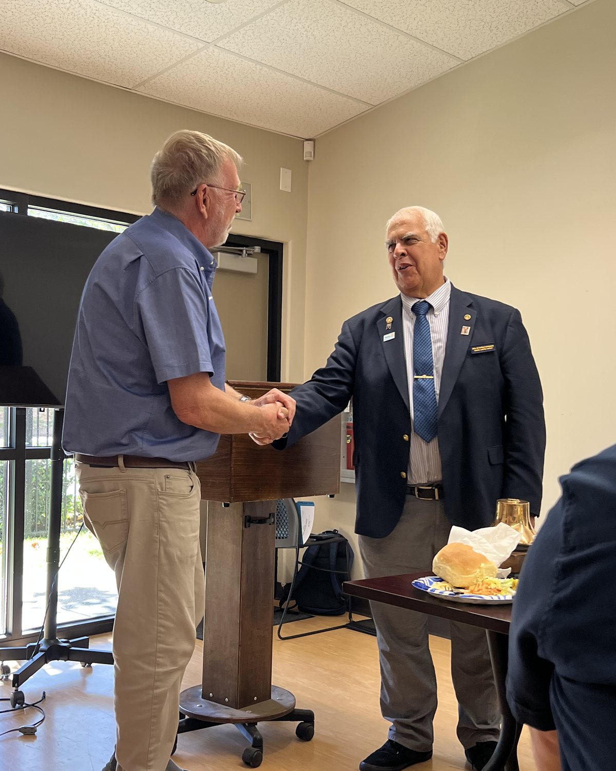 President Doug Emery and District Governor Richard Lemire shake hands across the podium at the Chatigny Center