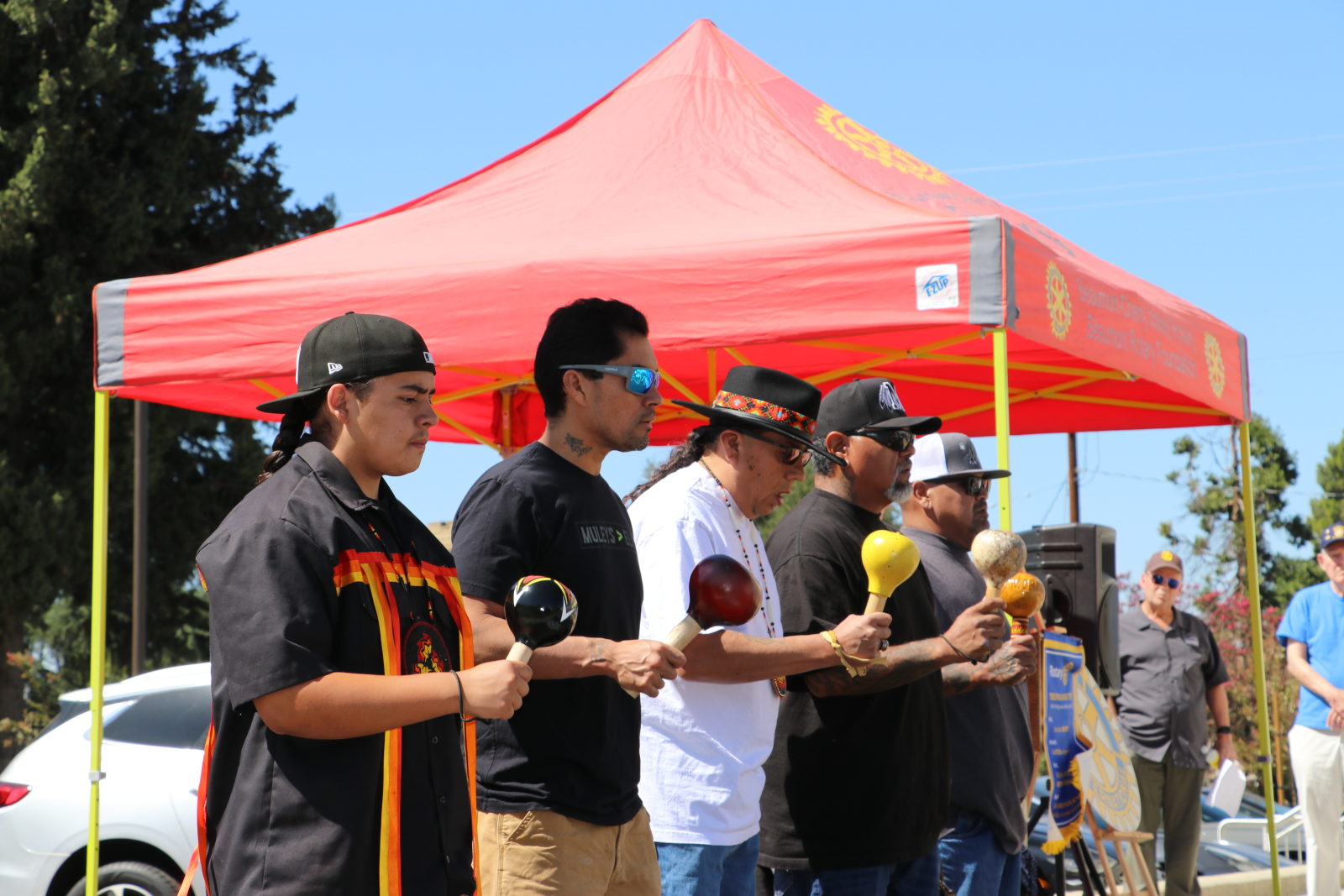 Members of the Morongo Bird Singing Group, holding gourd rattles, sing beneath the club's red canopy to open the ceremony