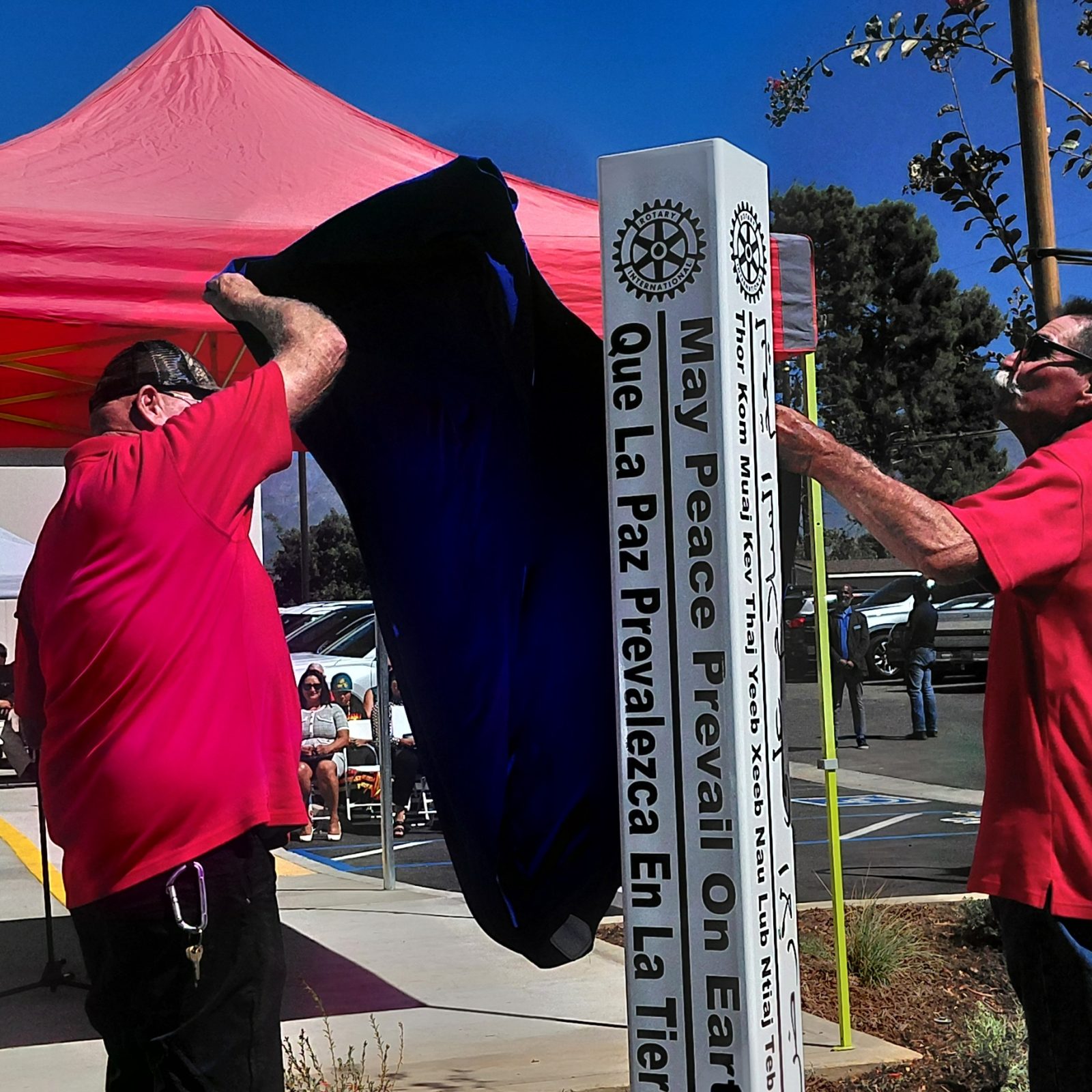 Two Rotarians pull the cover off Beaumont's second Peace Pole outside the Beaumont Library